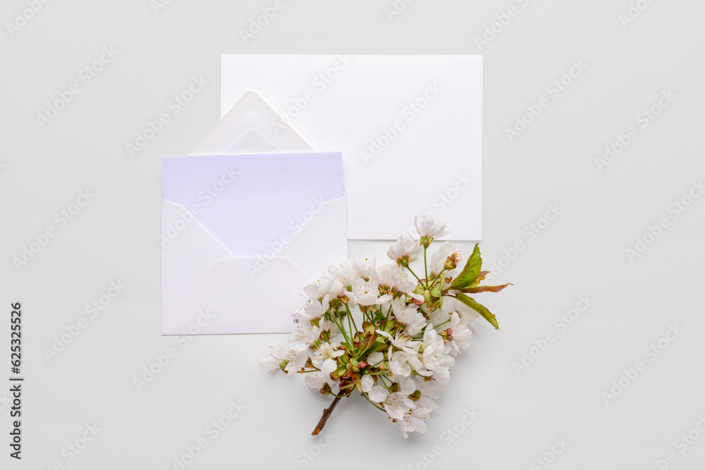 Paper envelopes with blank card and blooming tree branch on white background