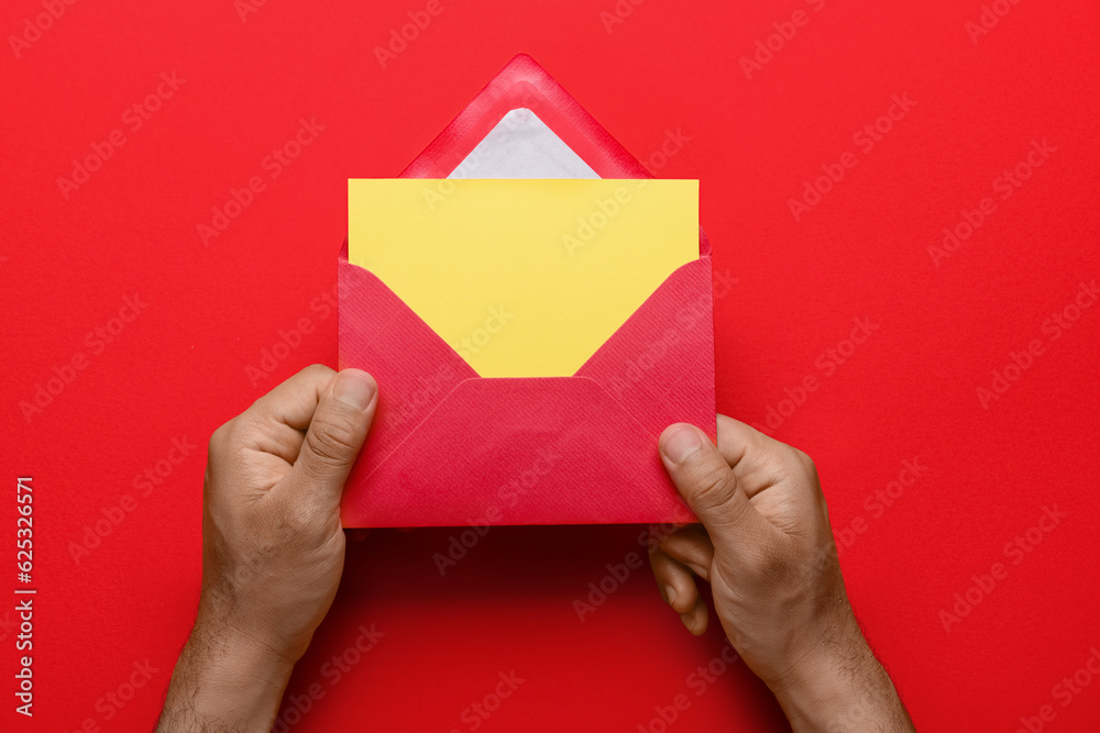 Male hands with envelope and blank card on red background, closeup