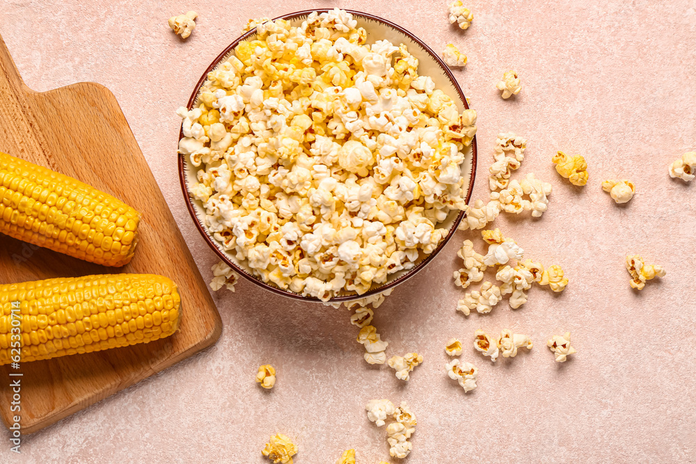 Bowl with tasty popcorn on pink background