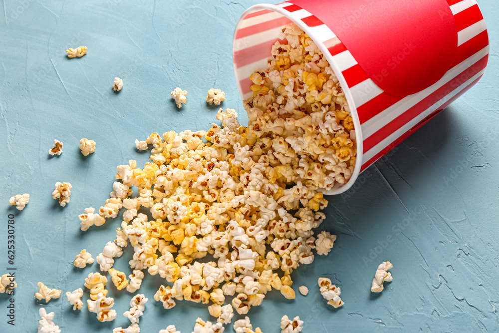 Bucket with tasty popcorn on blue background