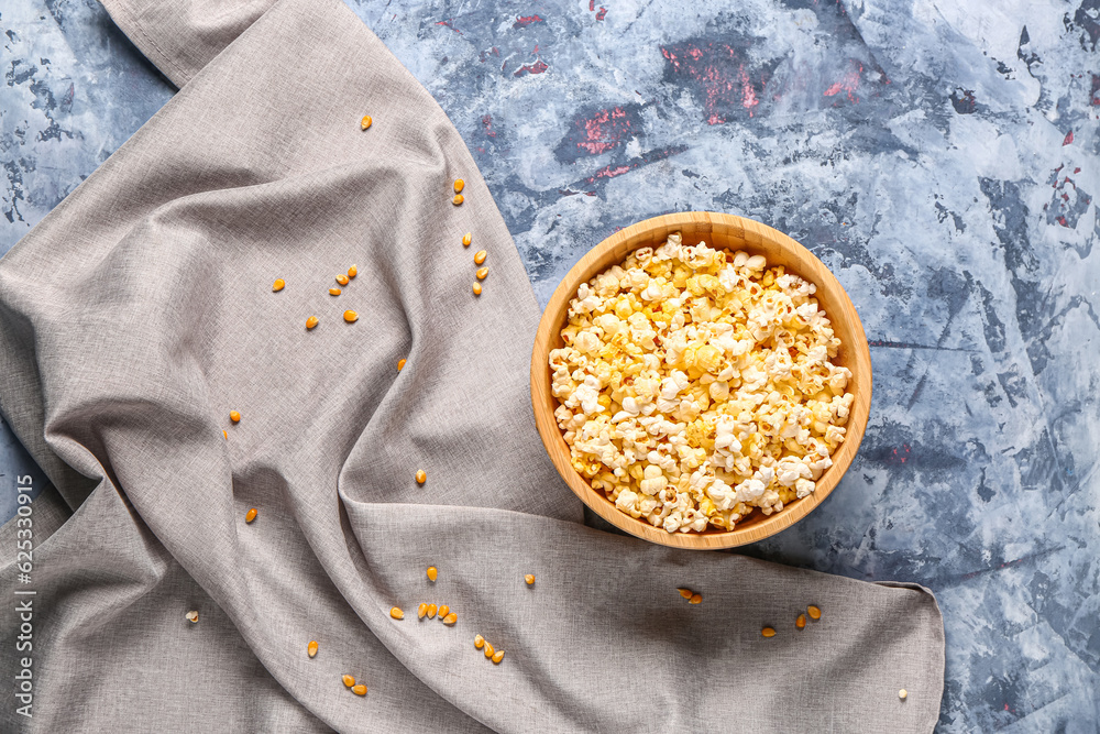 Bowl with tasty popcorn on blue background