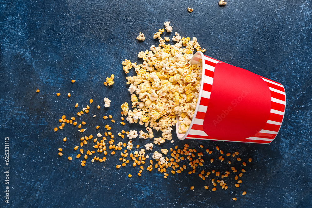 Bucket with tasty popcorn on blue background