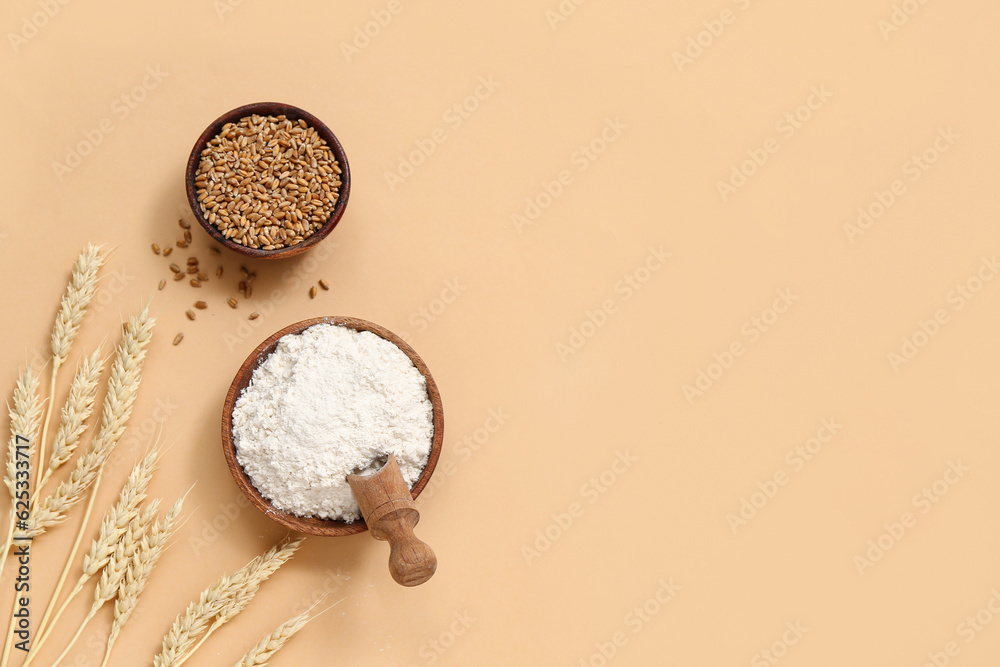 Bowls with wheat flour and grains on beige background