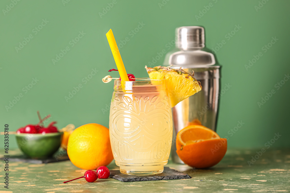 Glass of tasty mai tai cocktail on green background