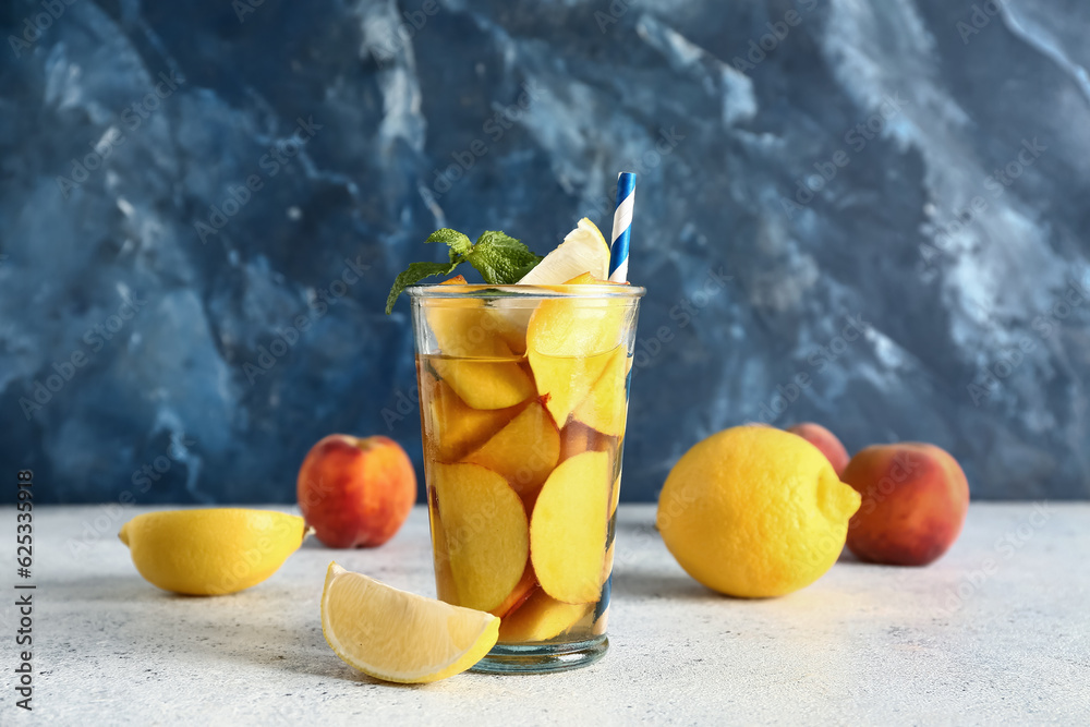 Glass of fresh peach lemonade with mint on white table