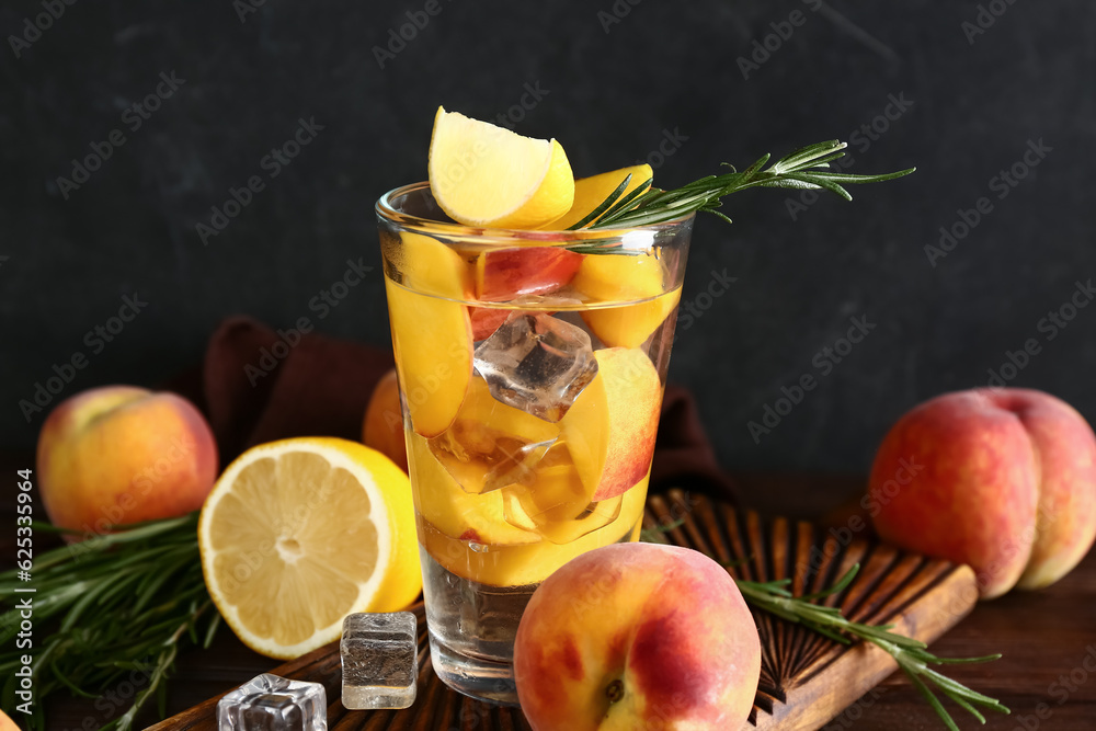 Board with glass of fresh peach lemonade and rosemary on wooden table