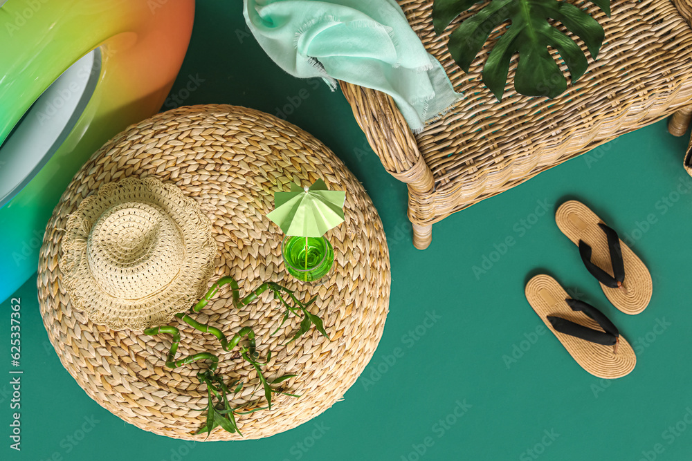 Beach accessories, glass of cocktail and bamboo branches on color background