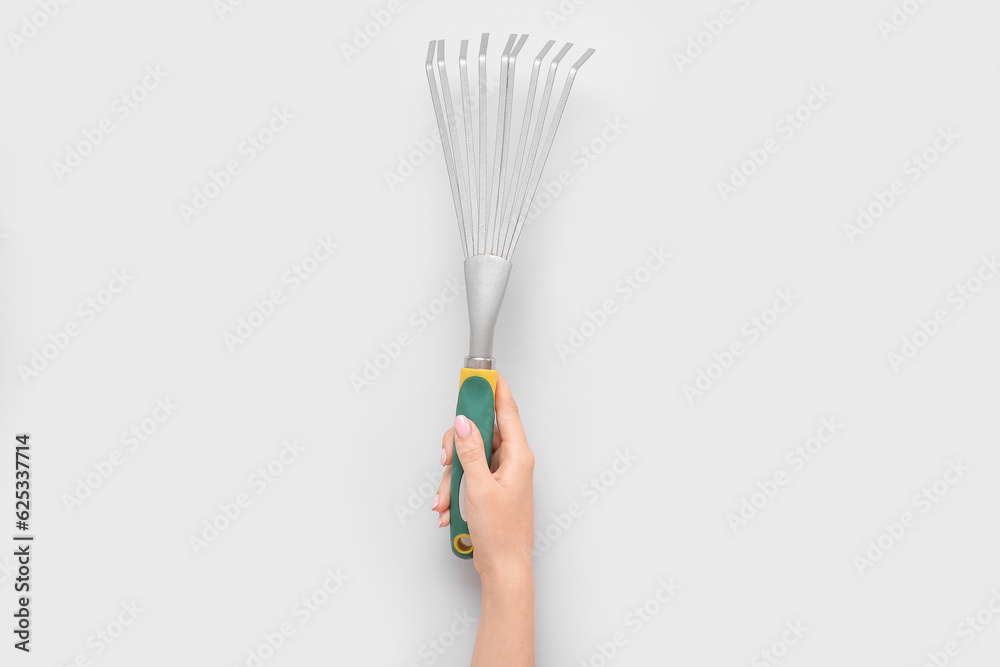 Woman with gardening rake on grey background