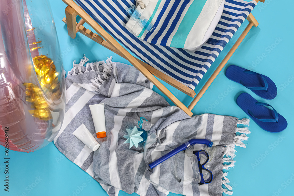 Deckchair, inflatable ring and glass of cocktail on blue background