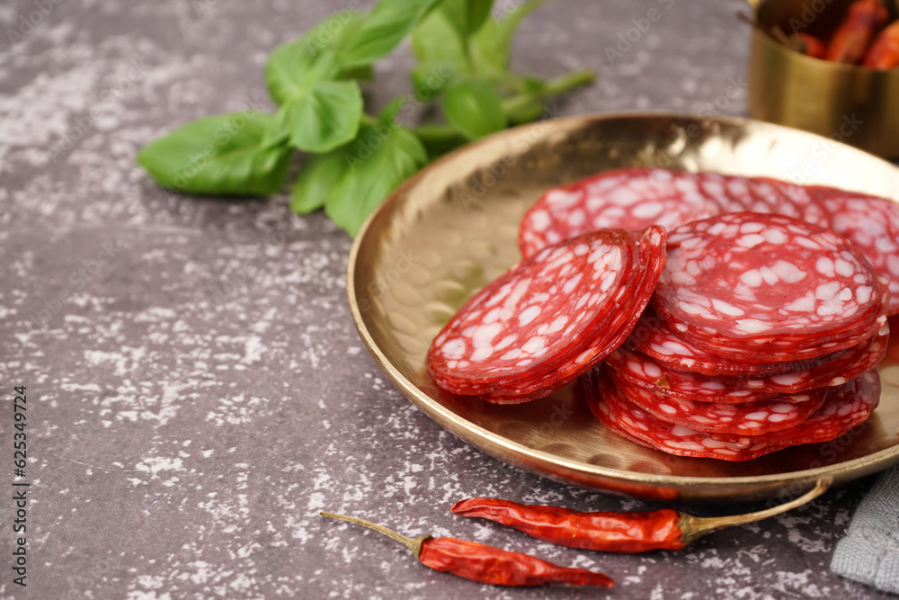 Plate with slices of tasty salami on grey background