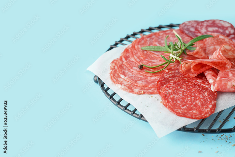 Grid with slices of tasty salami on blue background