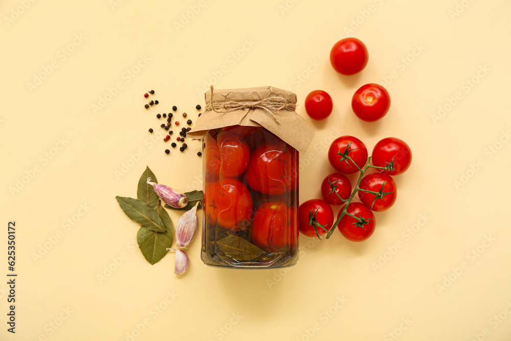 Jar with canned tomatoes and garlic on beige background