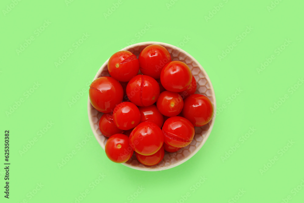 Bowl with canned tomatoes on green background