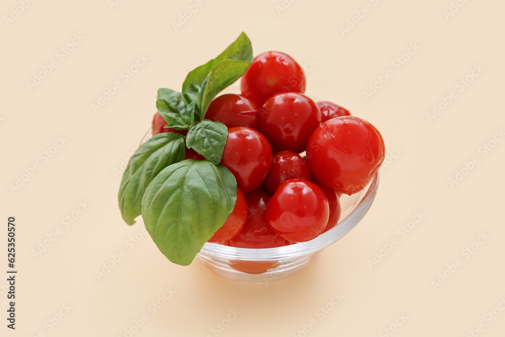 Glass bowl with canned tomatoes and basil on yellow background