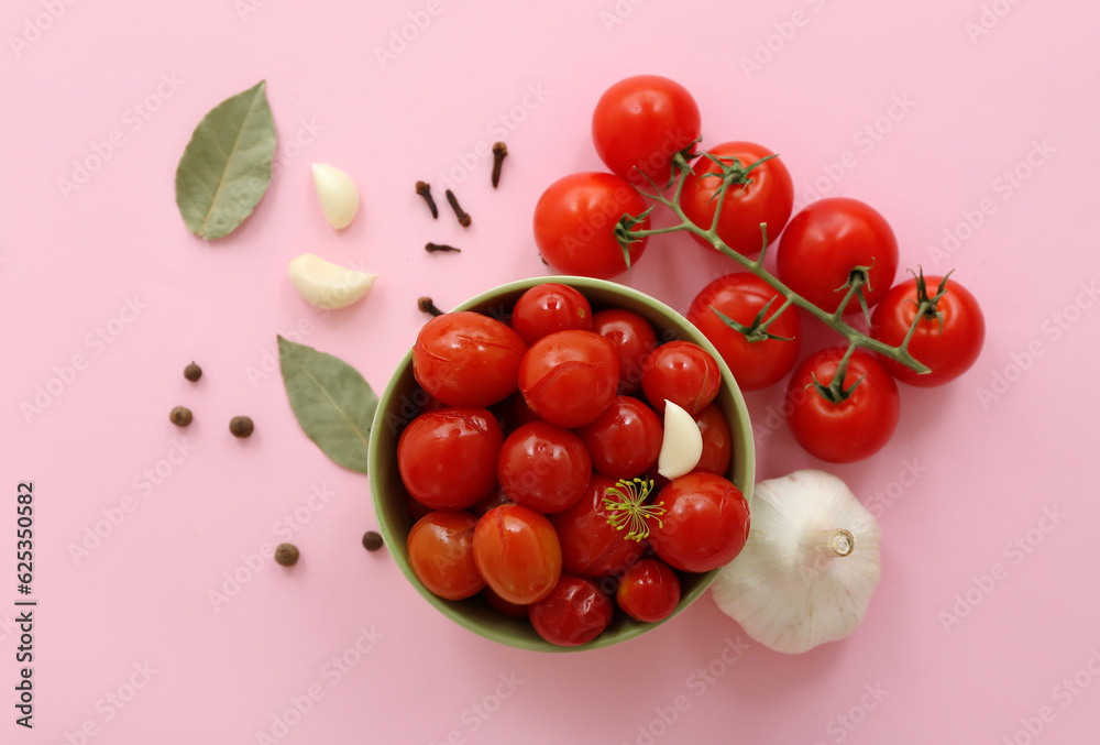 Bowl with canned tomatoes and garlic on pink background