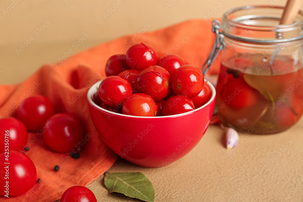 Bowl and jar with canned tomatoes on brown background