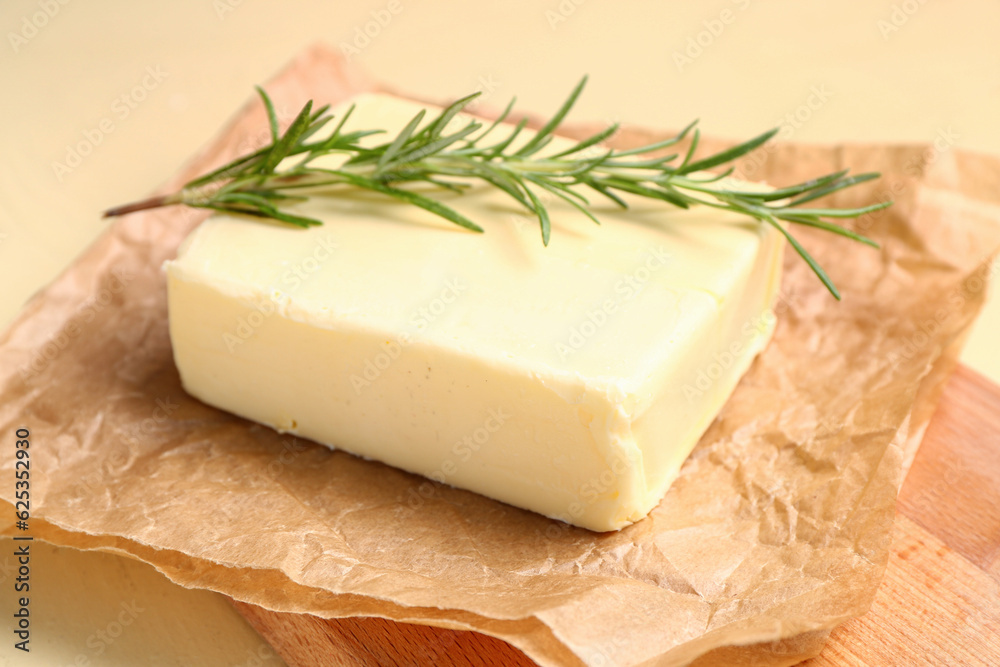 Baking paper with fresh butter and rosemary on yellow background