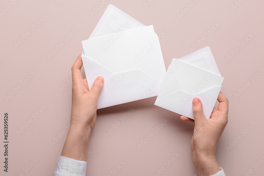 Female hands with paper envelopes and blank cards on color background, closeup