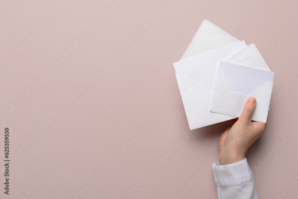 Female hand with envelopes and blank cards on color background