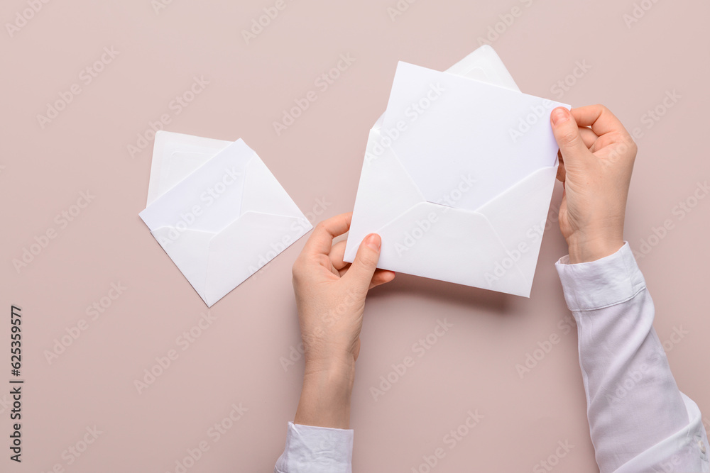 Female hands with paper envelopes and blank cards on color background, closeup