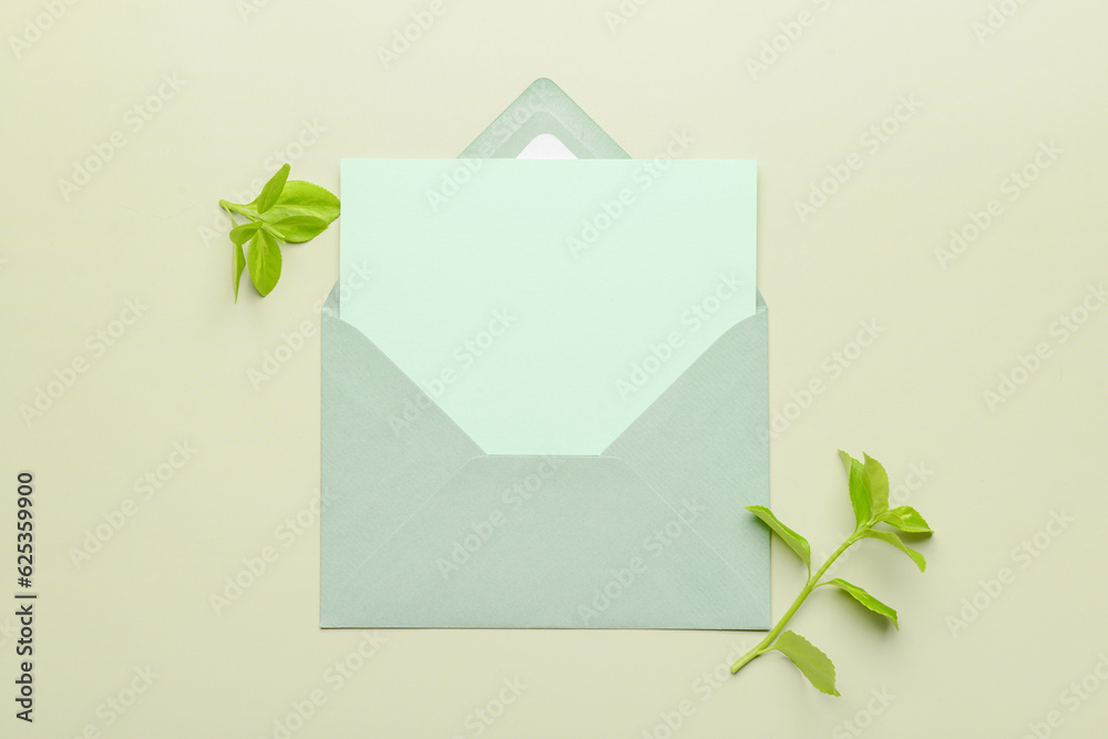 Envelope with blank card and plant branches on color background