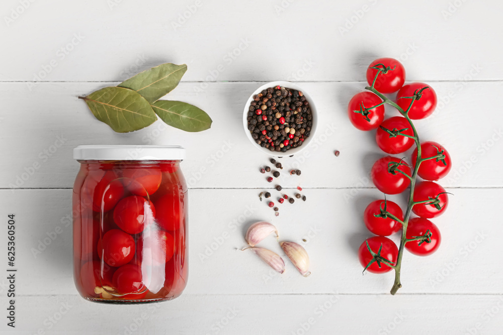 Jar with canned tomatoes, garlic and peppercorn on white wooden table