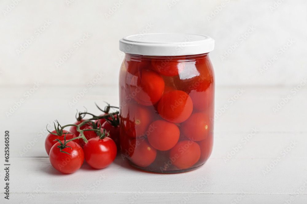 Jar with canned tomatoes on white wooden table