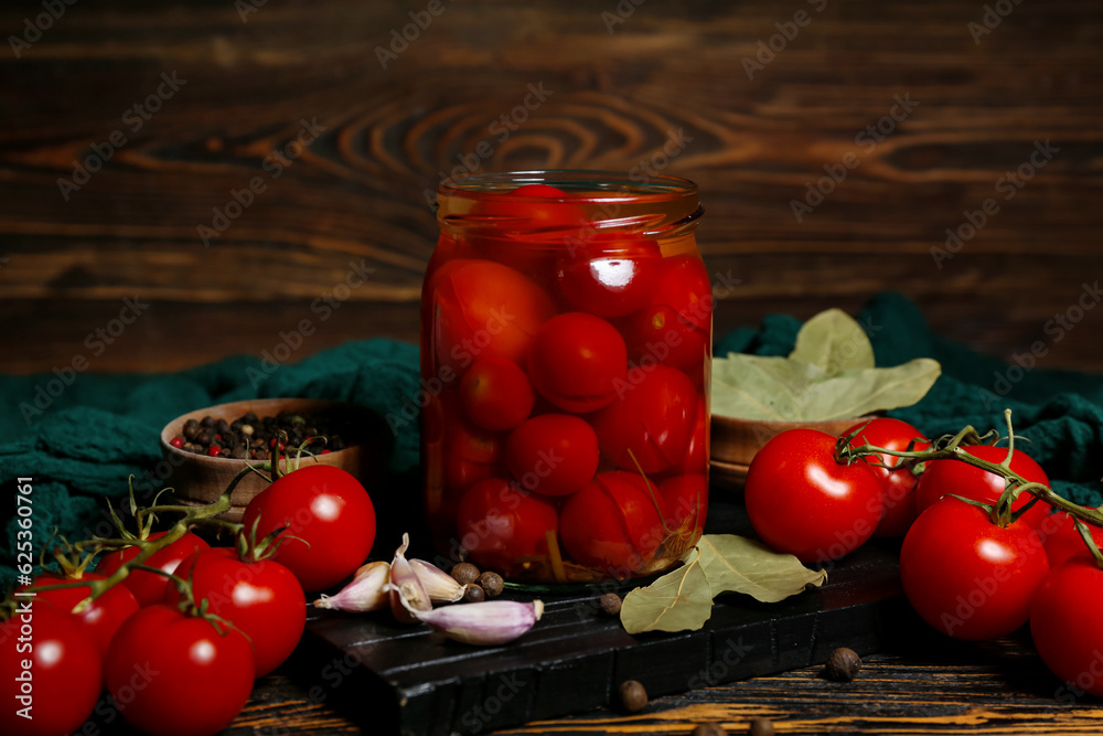 Jar with canned tomatoes and garlic on wooden background