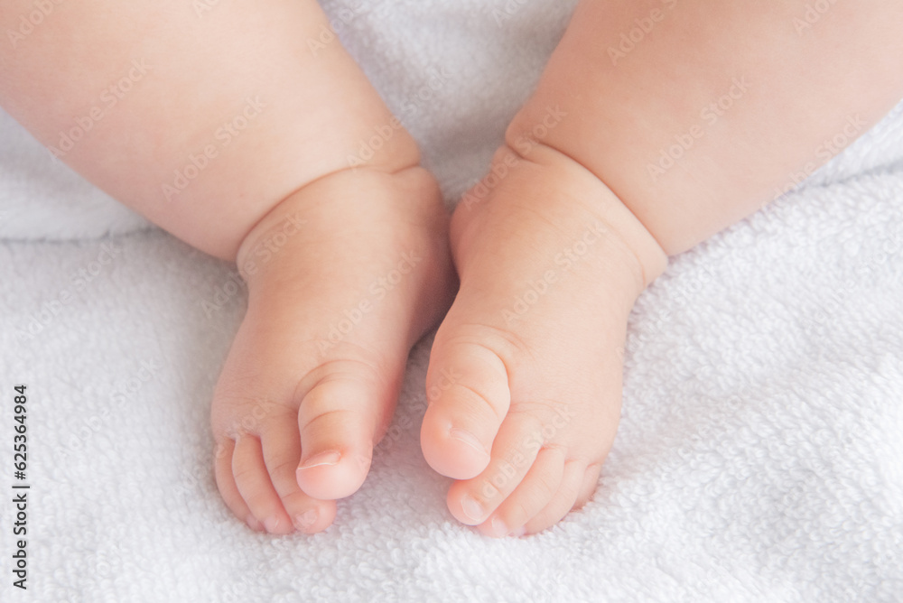 Tiny newborn baby feet closeup on a white blanket