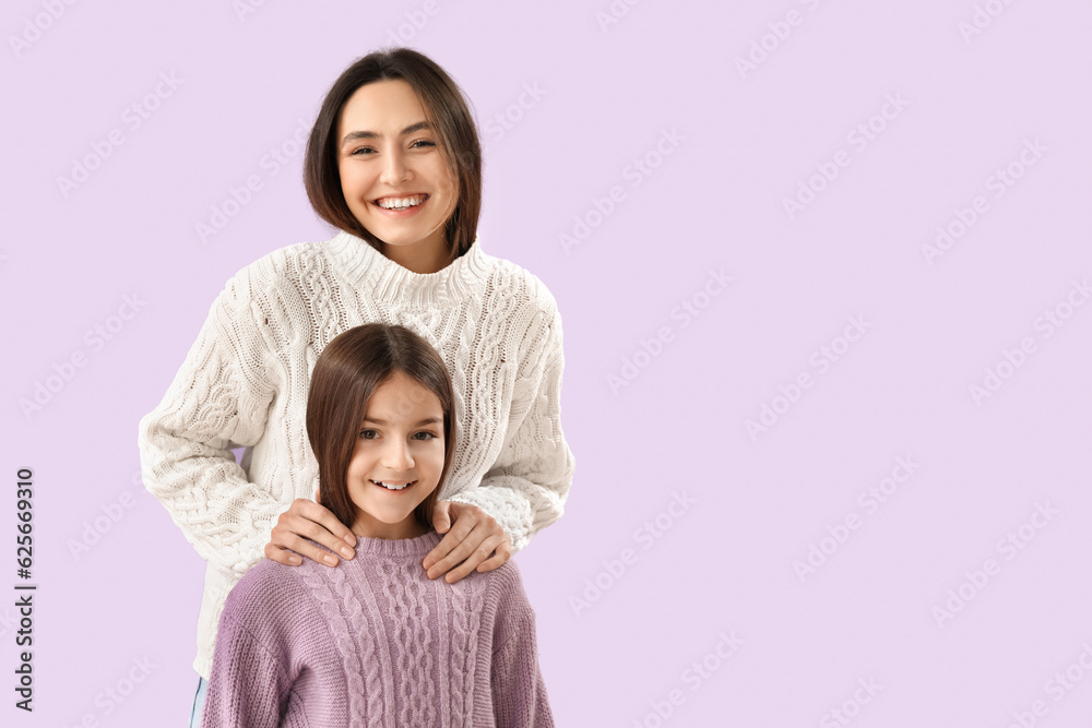 Little girl and her mother in warm sweaters on lilac background