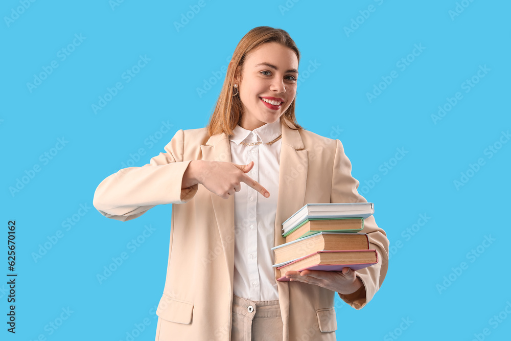 Young woman pointing at books on blue background