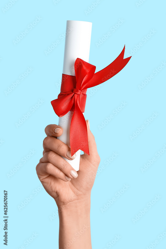 Woman holding diploma with ribbon on blue background