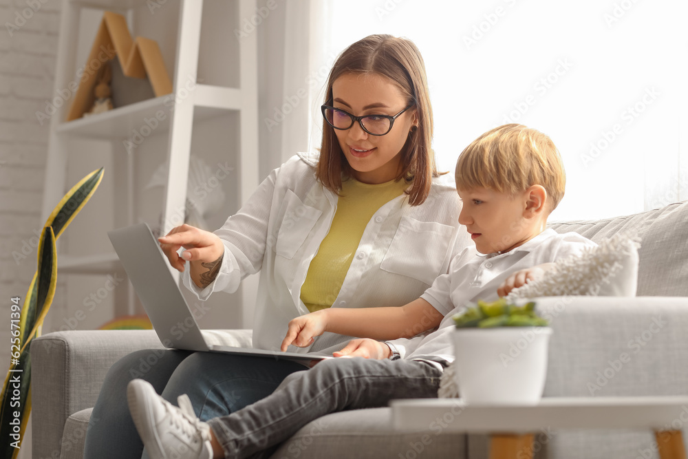 Nanny with little boy watching cartoons at home