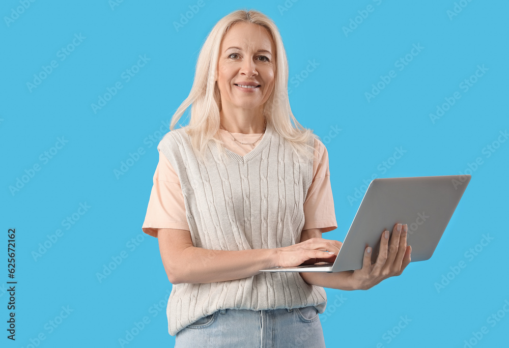 Mature female programmer working with laptop on blue background