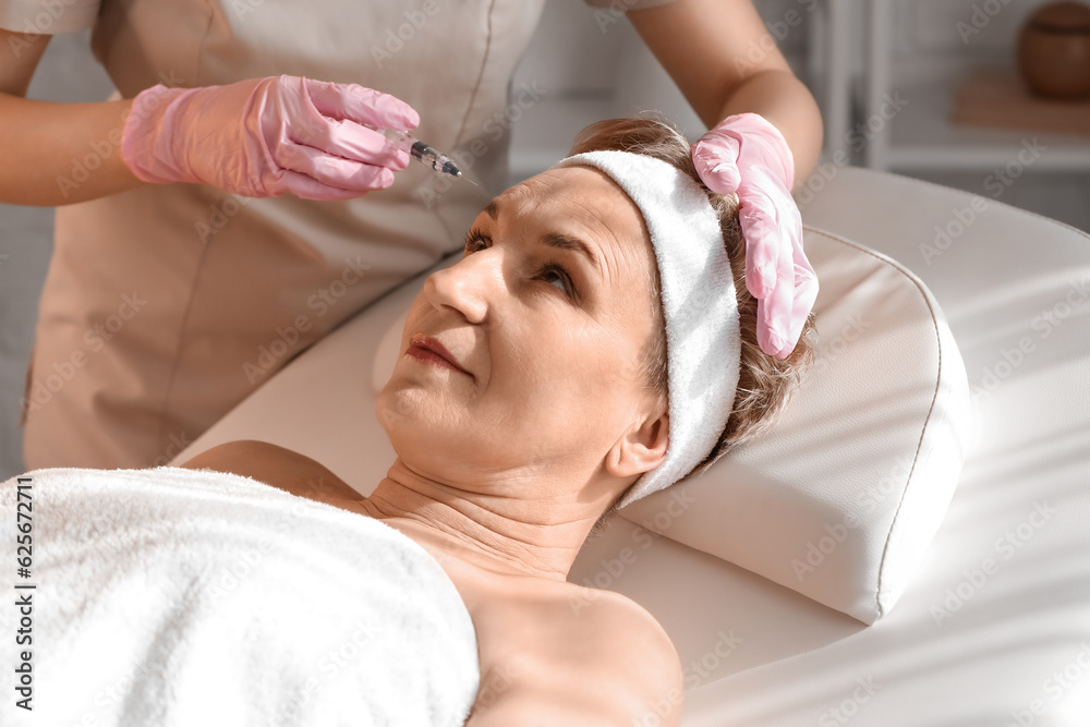 Mature woman receiving filler injection in beauty salon, closeup