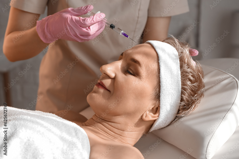 Mature woman receiving filler injection in beauty salon, closeup