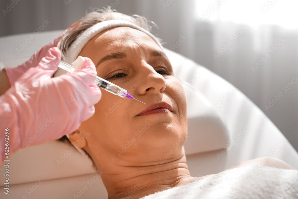 Mature woman receiving filler injection in beauty salon, closeup