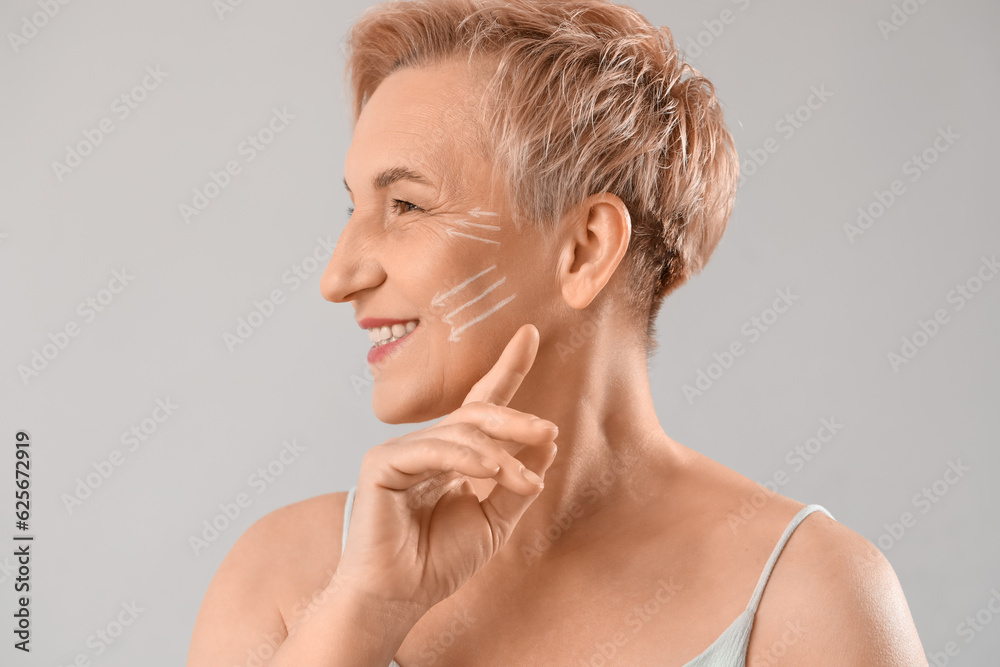 Mature woman with marked face for filler injection on light background, closeup