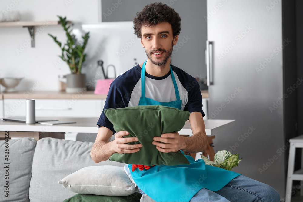 Young man fixing cushion at home