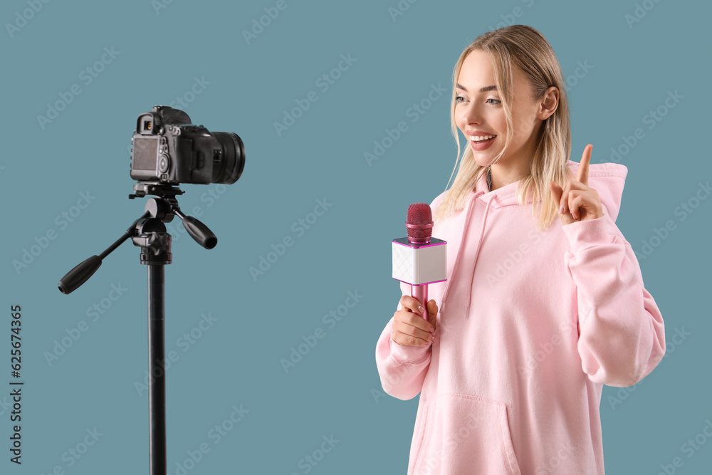 Female journalist with microphone recording video on blue background