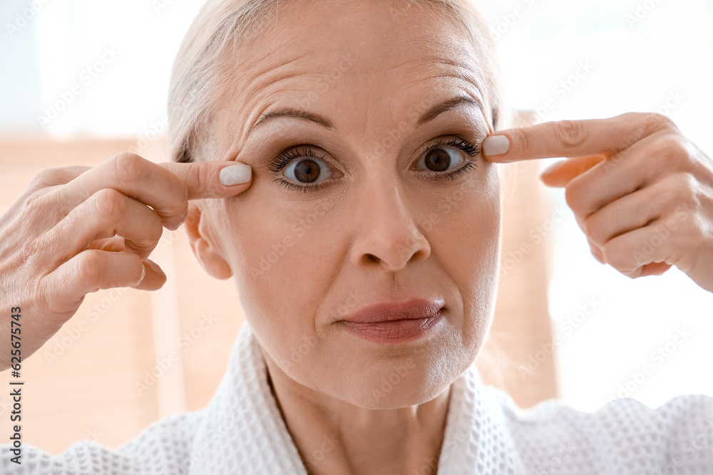 Mature woman doing face building exercise in bathroom, closeup