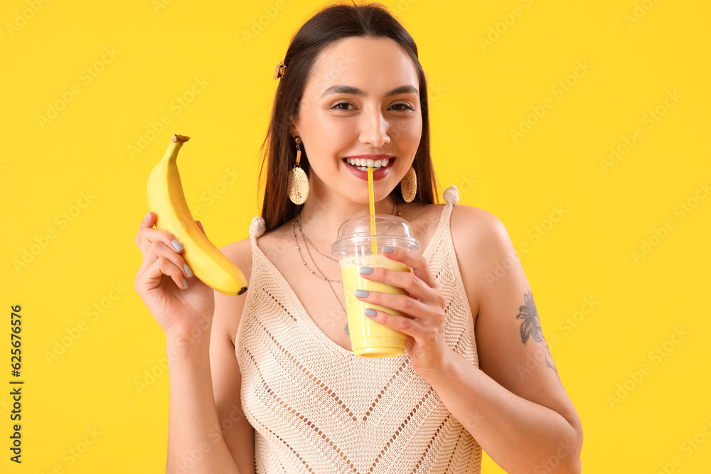 Young woman with glass of smoothie and banana on yellow background