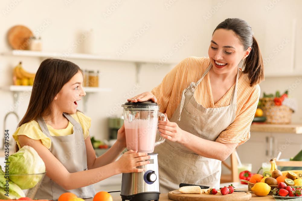 Little girl and her mother making smoothie with blender in kitchen