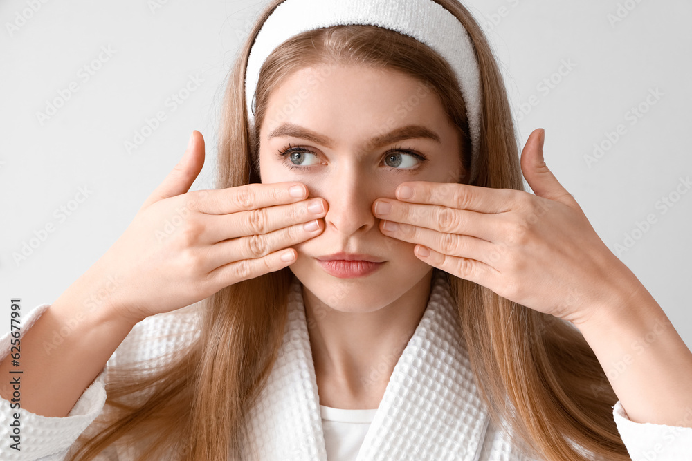 Young woman doing face building exercise on light background, closeup