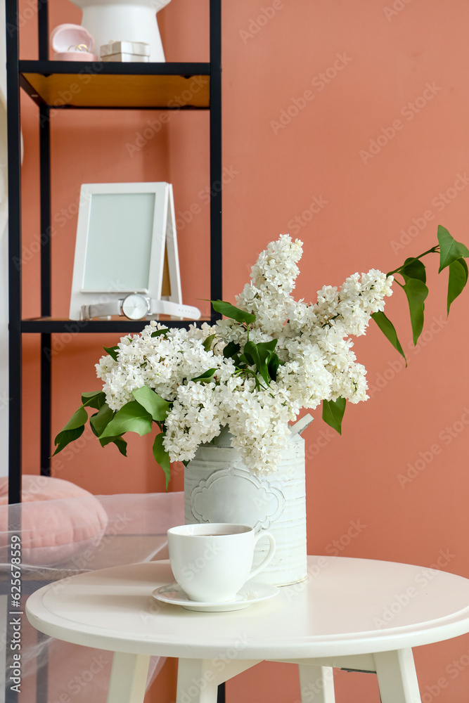 Vase with lilac flowers and cup of coffee on table in dressing room