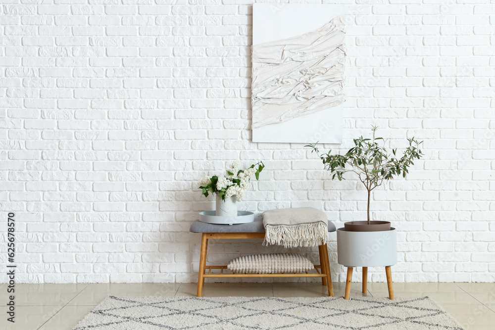 Interior of light room with soft bench and lilac flowers in vase