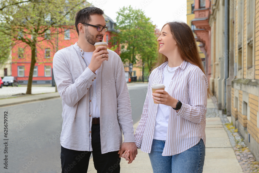 Beautiful loving happy couple drinking coffee and walking in city on spring day