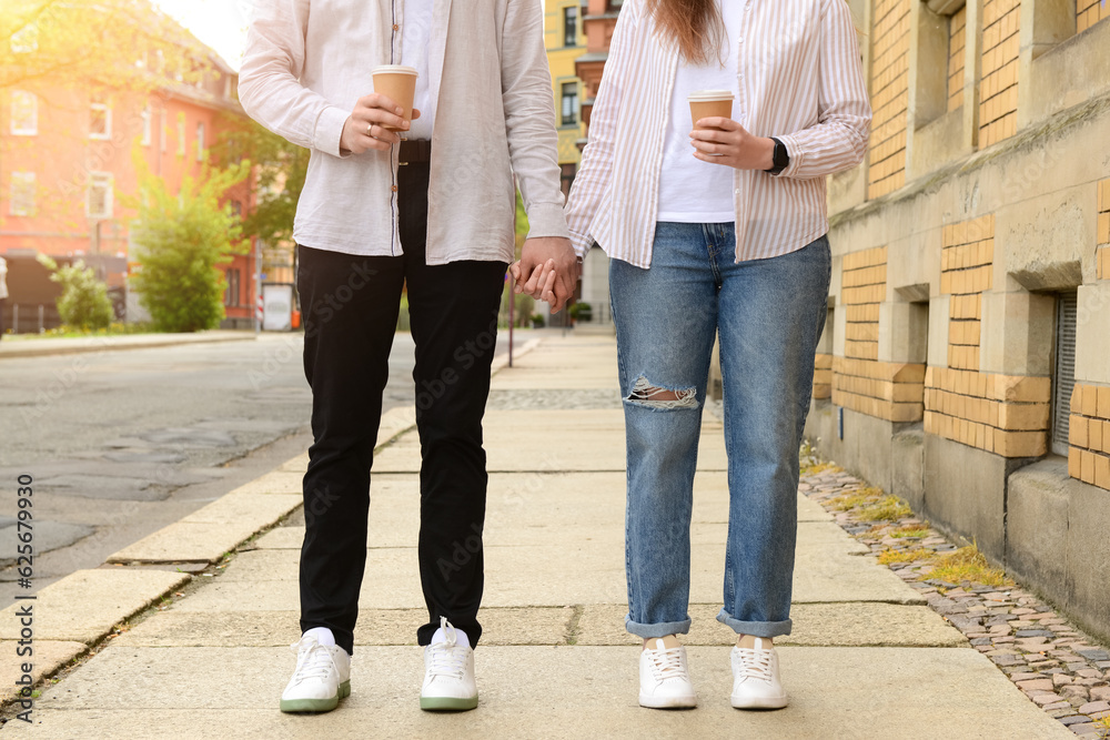 Beautiful loving happy couple drinking coffee and walking in city on spring day