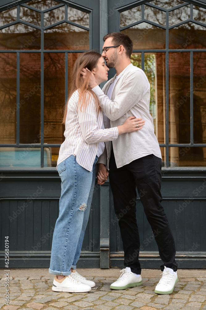 Young man kissing his girlfriend on her forehead in city