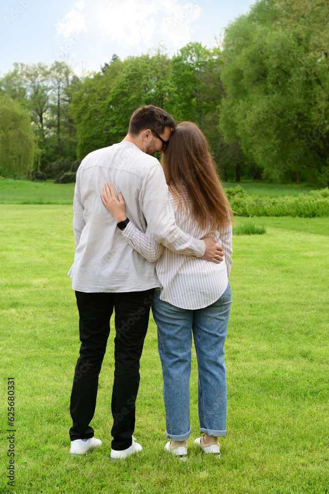 Beautiful loving couple hugging and walking in park on spring day